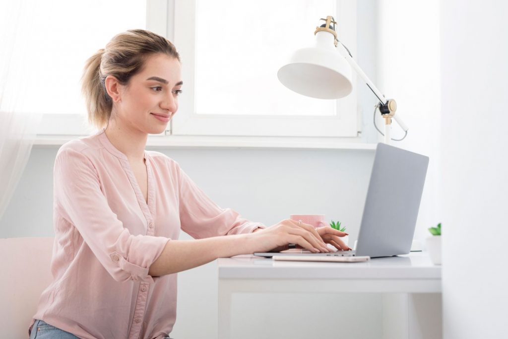 A woman working on a laptop in a bright workspace — showing how Affiliate Marketing allows earning online from home with digital tools.